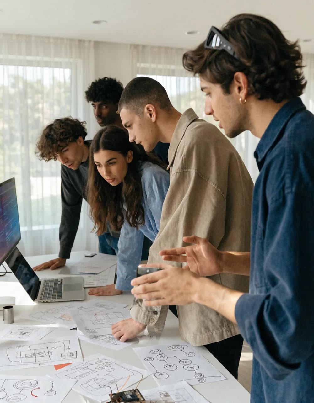 Founders building together with laptops and screens.