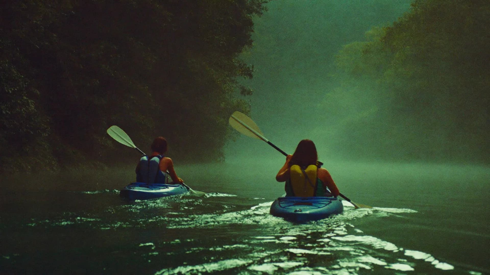 Kayaks on a river in a green gorge, morning mist on the water.